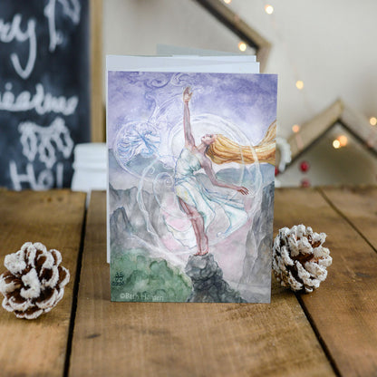 mother goddess art greeting card 5x7 with envelope standing on  rustic table with pine cones and lights in the background