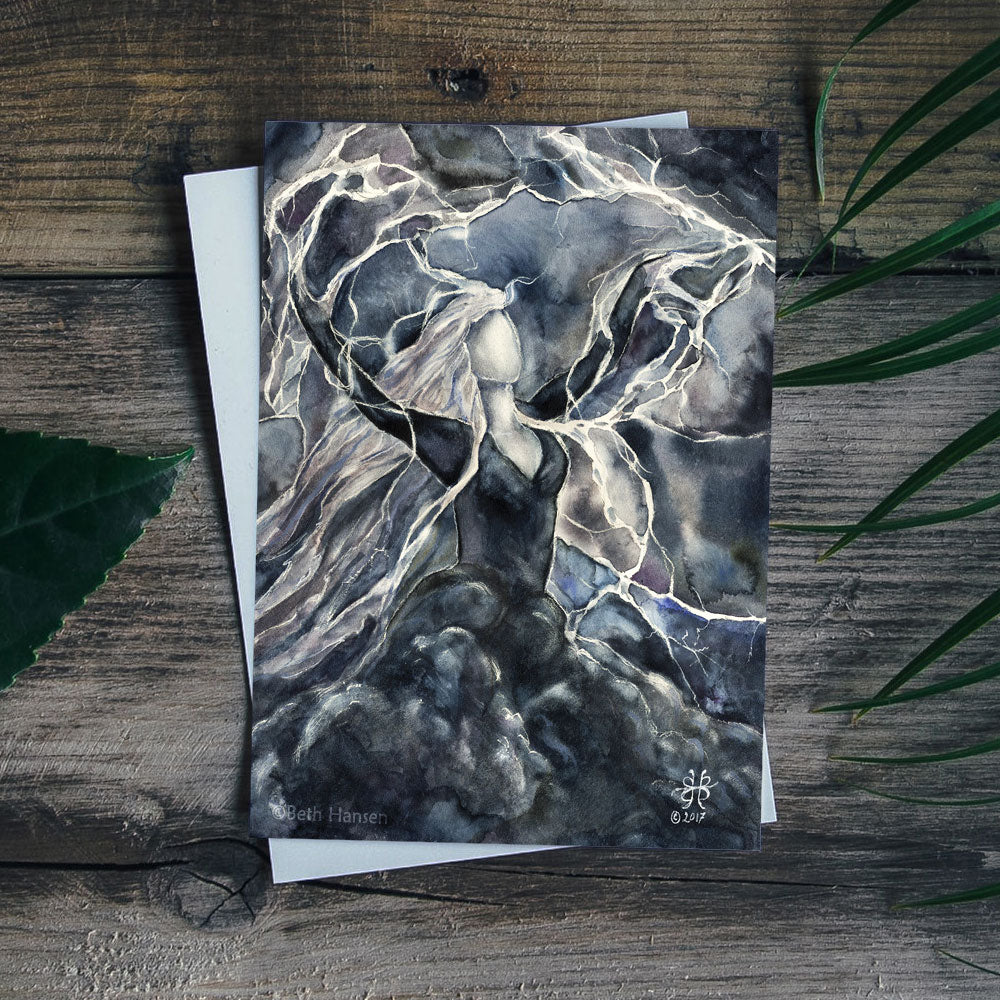 Storm Goddess greeting card  and white envelope on dark rustic wood background with leaves